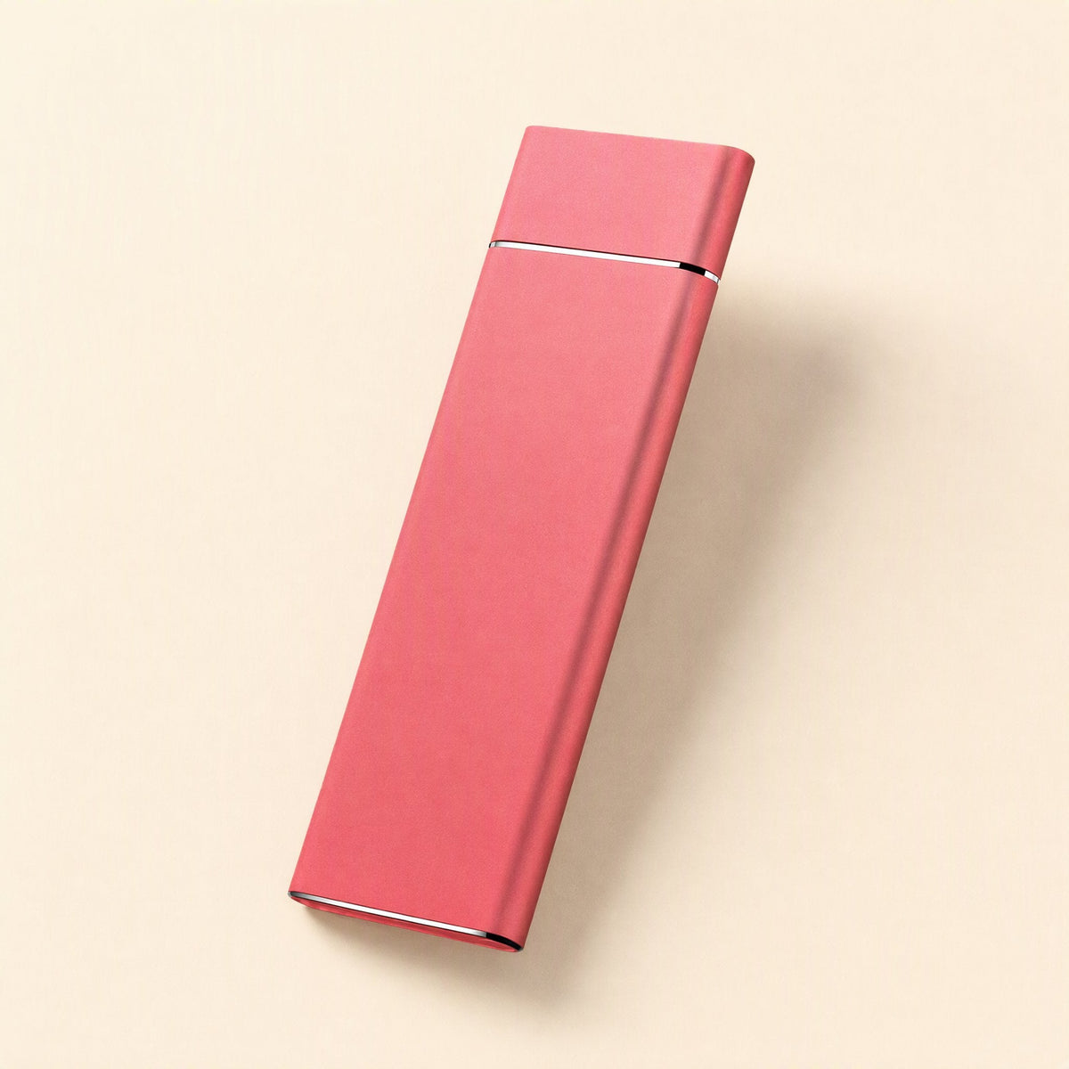 Pocketdrive External Solid State Drive – slim coral-red aluminum drive resting at an angle on a pale cream background
