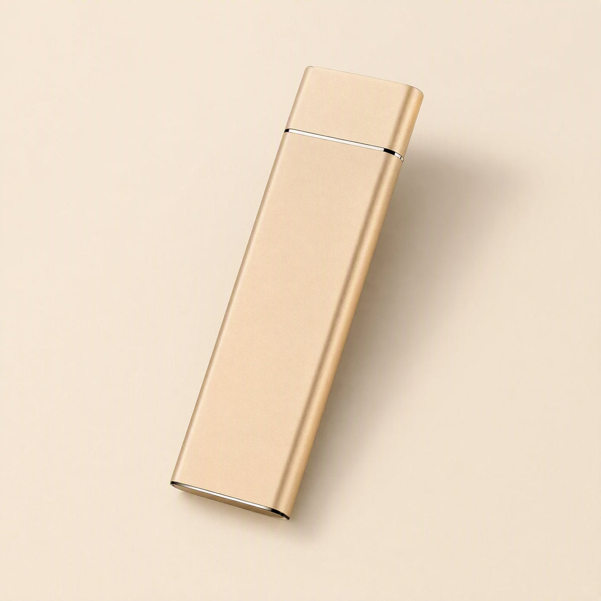 Driveglide – Gold-toned slim metal drive angled on a pale beige background, USB port end at the bottom