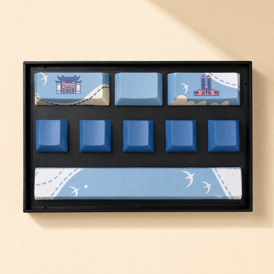Keycanvas – Light and dark blue keycap set with temple and tower icons and swallow patterns on the spacebar, in a tray