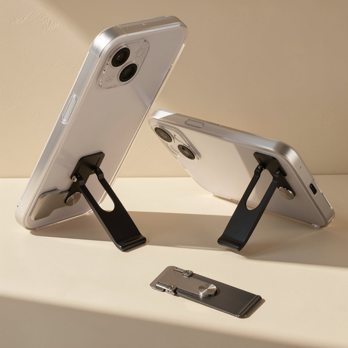 Spinstand – Two phones propped at different angles on black fold-out stands, with a folded stand lying in front