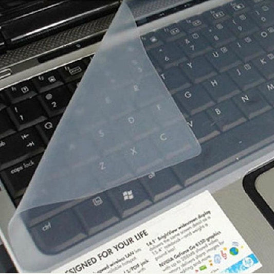 Keyfilm – Transparent silicone keyboard cover lifted at one corner over a black laptop keyboard with a sticker below