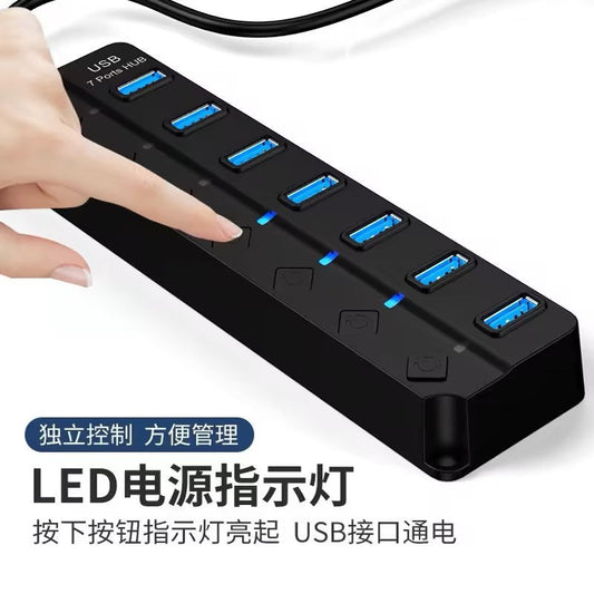Portpulse – Hand pressing a power button on a black 7-port USB hub, with blue LED indicators lit beside the ports