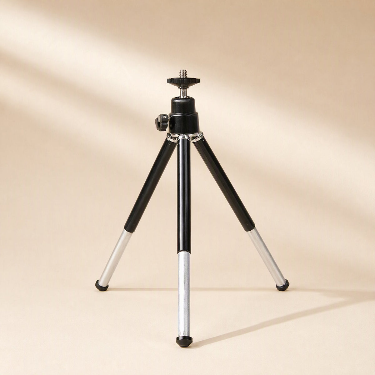 Phoneprop – Black ball-head tripod with extended silver legs and bare mounting screw, in soft diagonal light