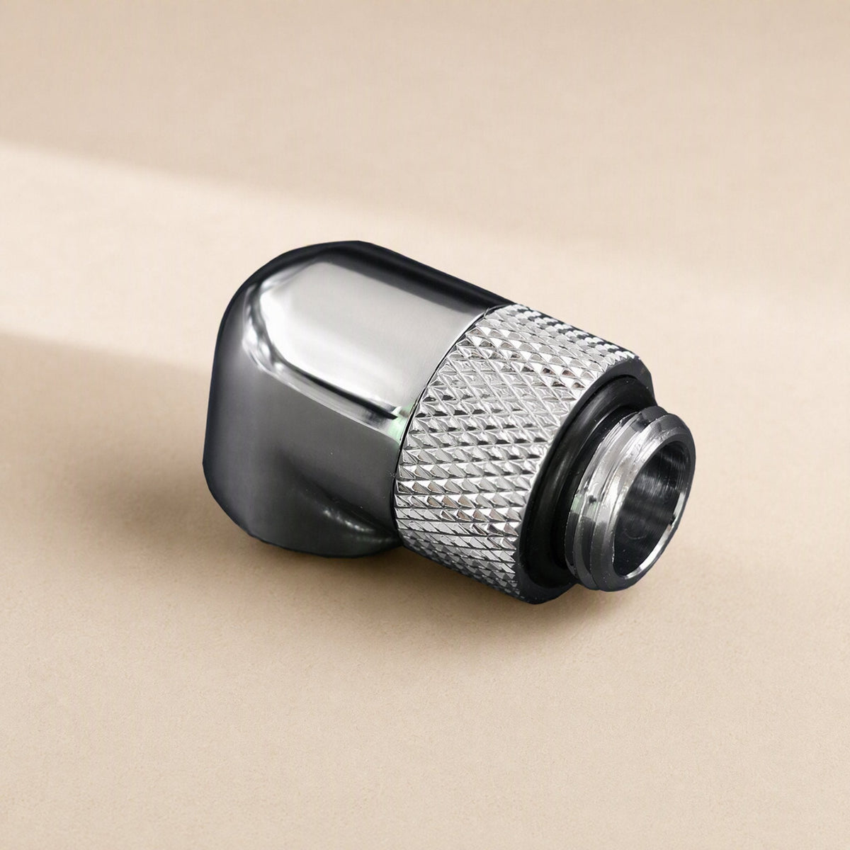 Swivelbend – Chrome 90-degree elbow fitting with a diamond-knurled swivel ring and male thread end, on a beige surface