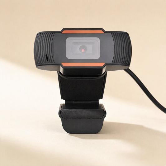 Clearcam – Front view of the webcam with its lens, ribbed sides and attached USB cable, standing on its clip base