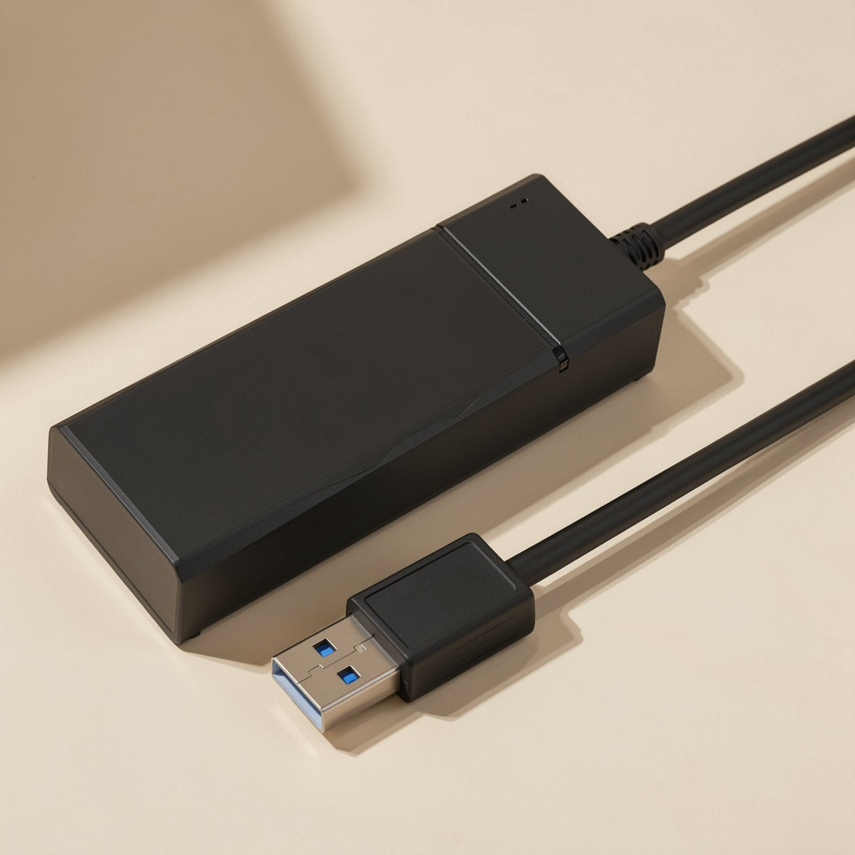 Portsplit – Black hub with a seam across one end, shown from above with the USB plug in the foreground on a cream backdrop