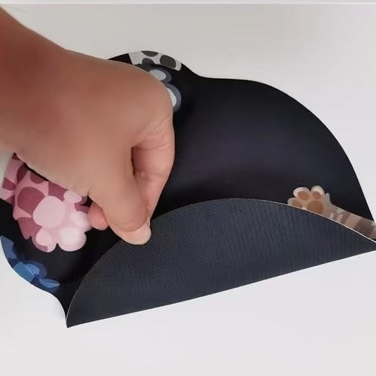 Clawpad – Hand peeling back the dark non-slip fabric underside of the paw print mouse pad on a white surface