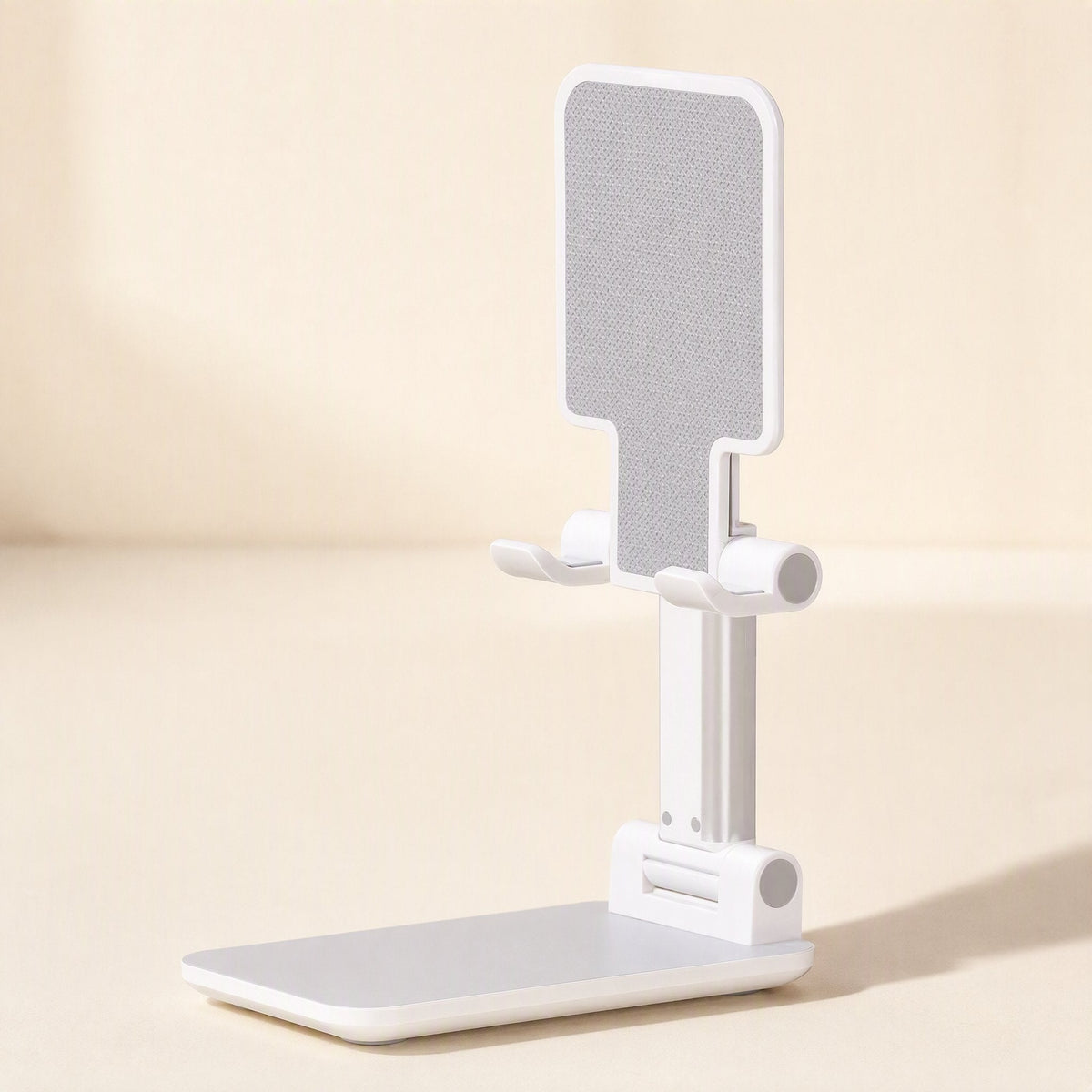 Pocketprop – White foldable phone stand raised upright on a cream background, front angle showing grip pad and base