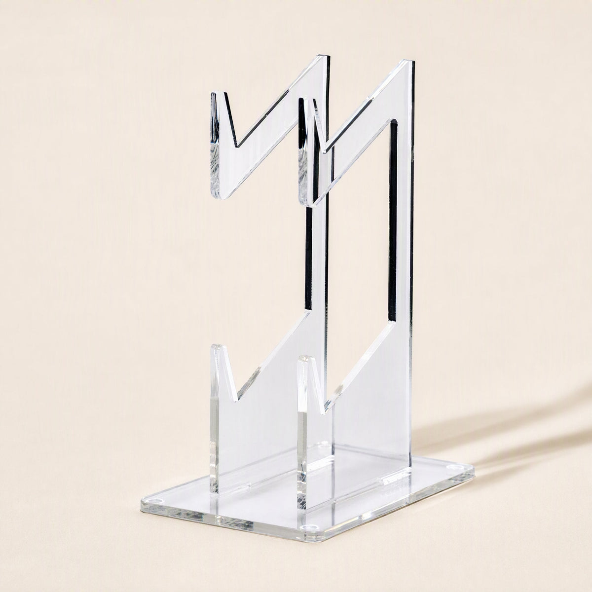Padstand – Rear three-quarter view of the clear acrylic stand showing the zigzag cradle arms and flat base