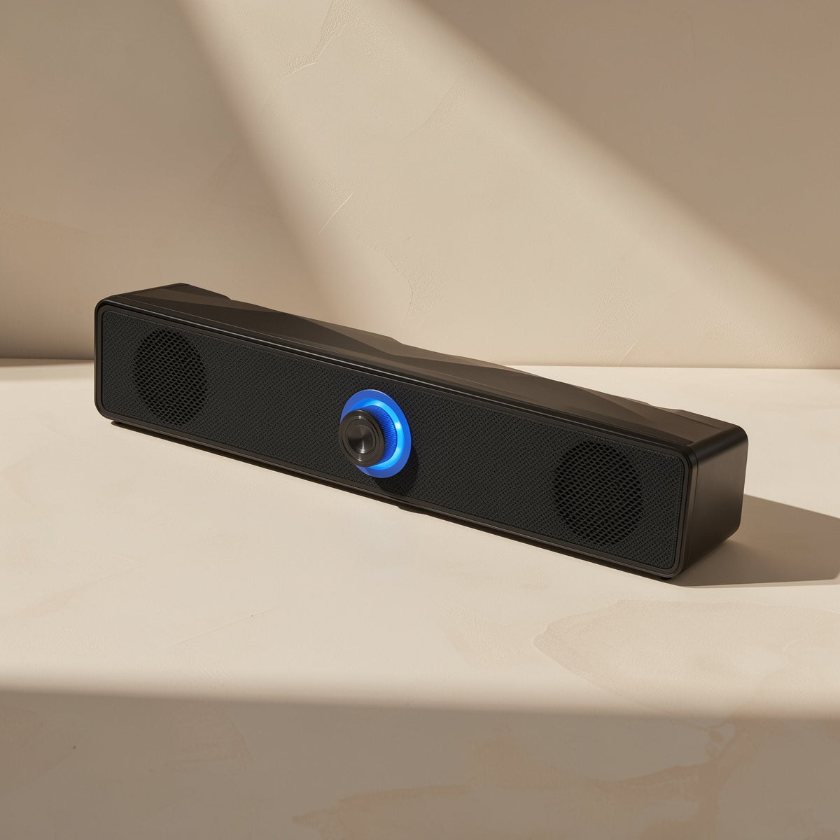 Deskbeat – Black bar speaker at an angle in sunlight, with two round side grilles and a glowing blue center knob
