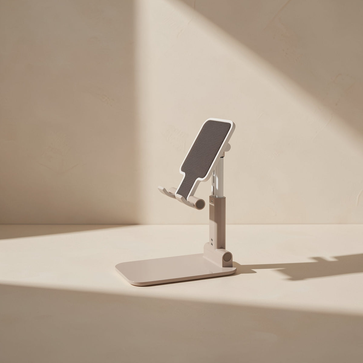 Foldstand – Single beige and white folding stand tilted at an angle, grey textured pad and base in sunlight
