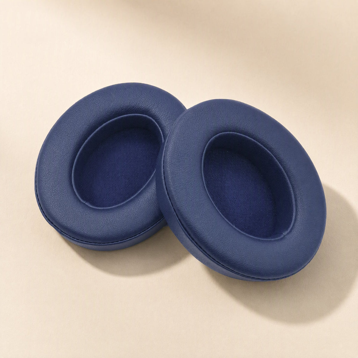 Leatherhug Headphone Covers – pair of navy blue imitation leather ear cushions lying side by side on a beige background