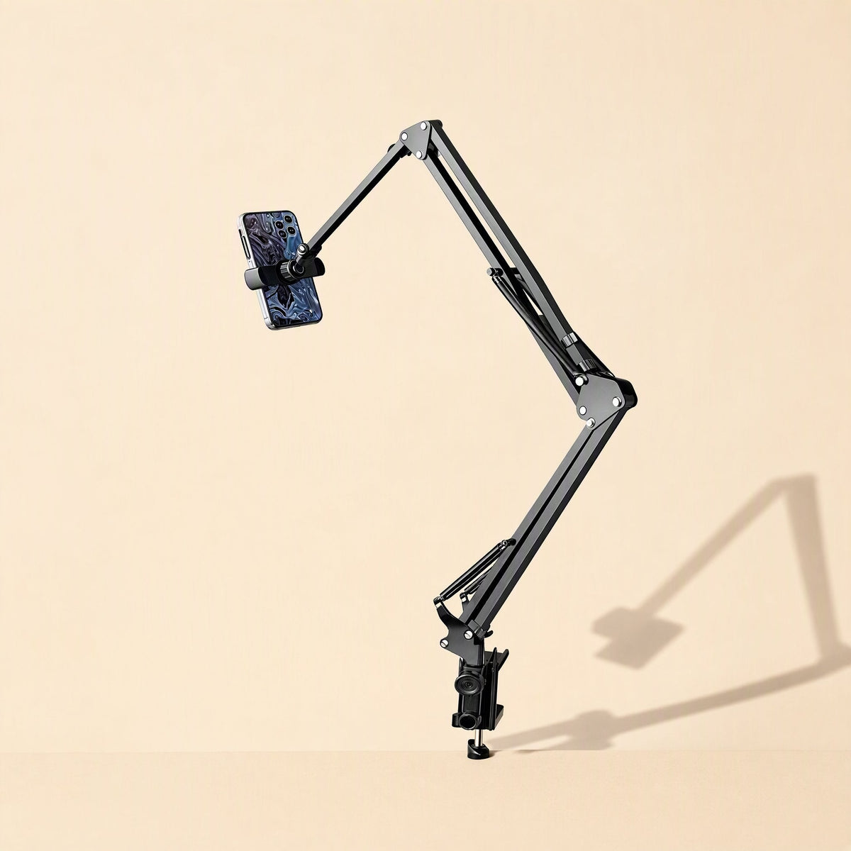 Metalhold – Tall black folding arm clamped to a desk edge, holding a smartphone with a patterned case, casting a shadow