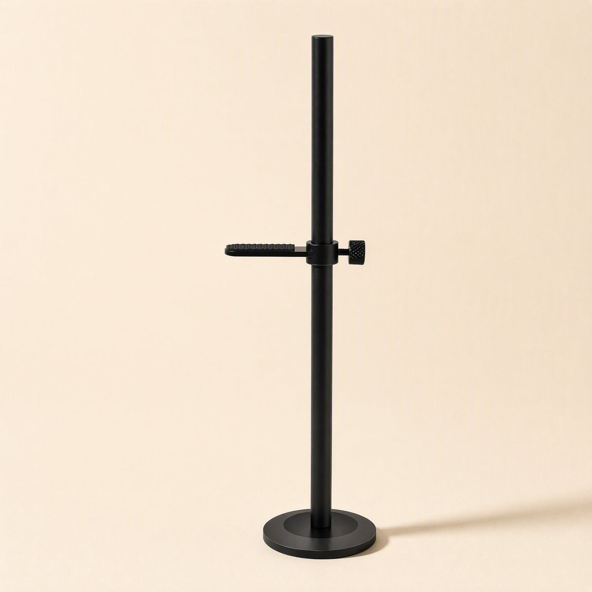 Magbrace – Black bracket with one textured arm and thumbscrew mounted on a round base, front view