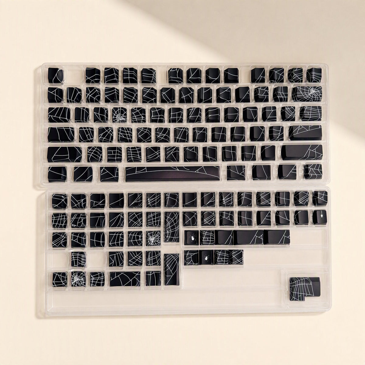 Webweave – Full set of black spider web keycaps with white web patterns laid out in clear plastic trays