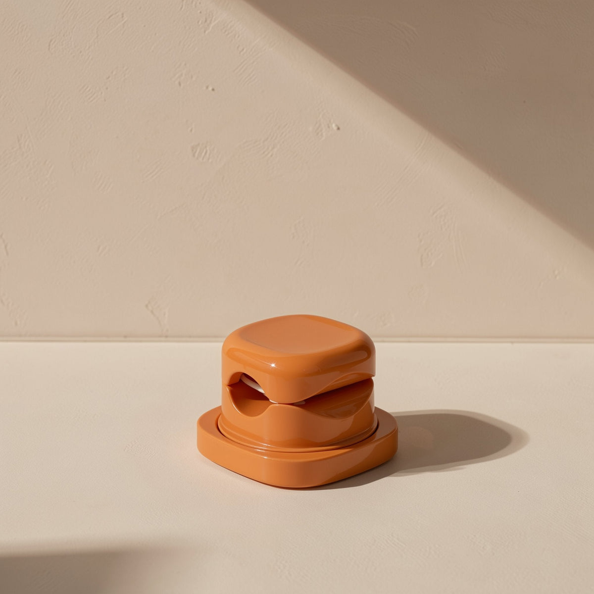 Spinsteady – Glossy terracotta organizer seen straight on, showing the two cable slots in its rounded stacked body