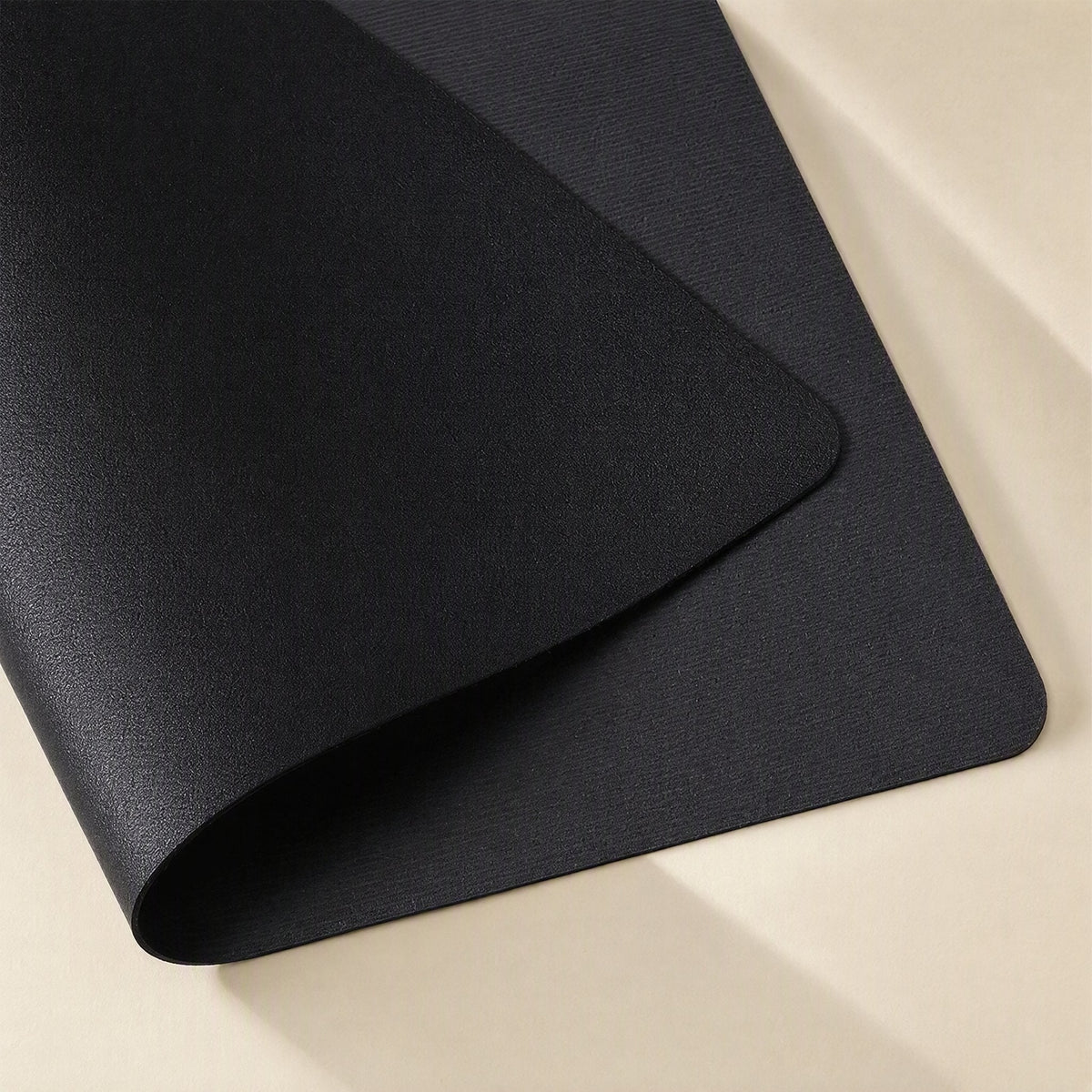 Smoothpad – Close-up of a black desk mat with one corner folded over, showing the textured leather surface