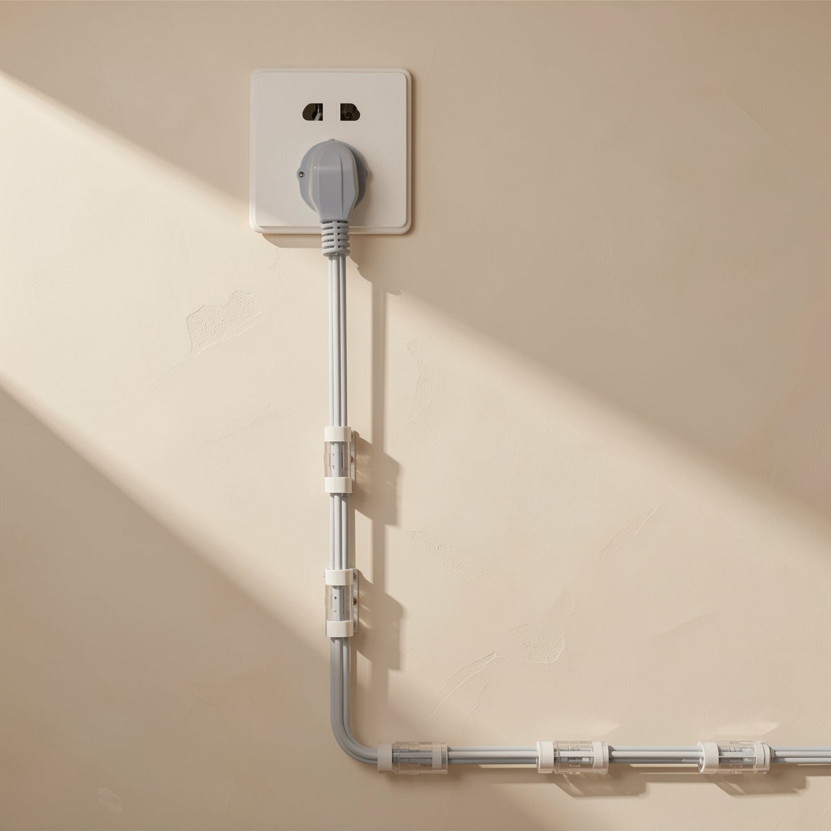 Stickcord – Gray power cord from a wall outlet run down and along the wall with clear cable clips spaced along it