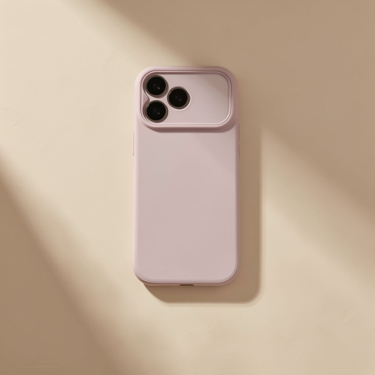 Gripcup – Plain blush pink phone case with triple camera cutout lying flat on a warm beige surface in soft light