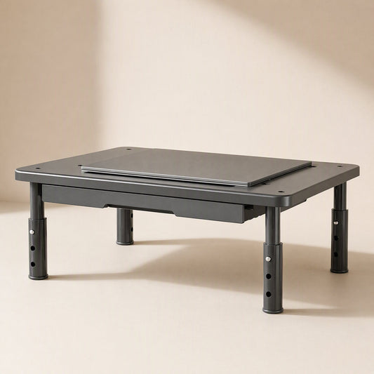 Risecrest – Front view of the riser in dark gray with a laptop on top, adjustable legs and a drawer underneath