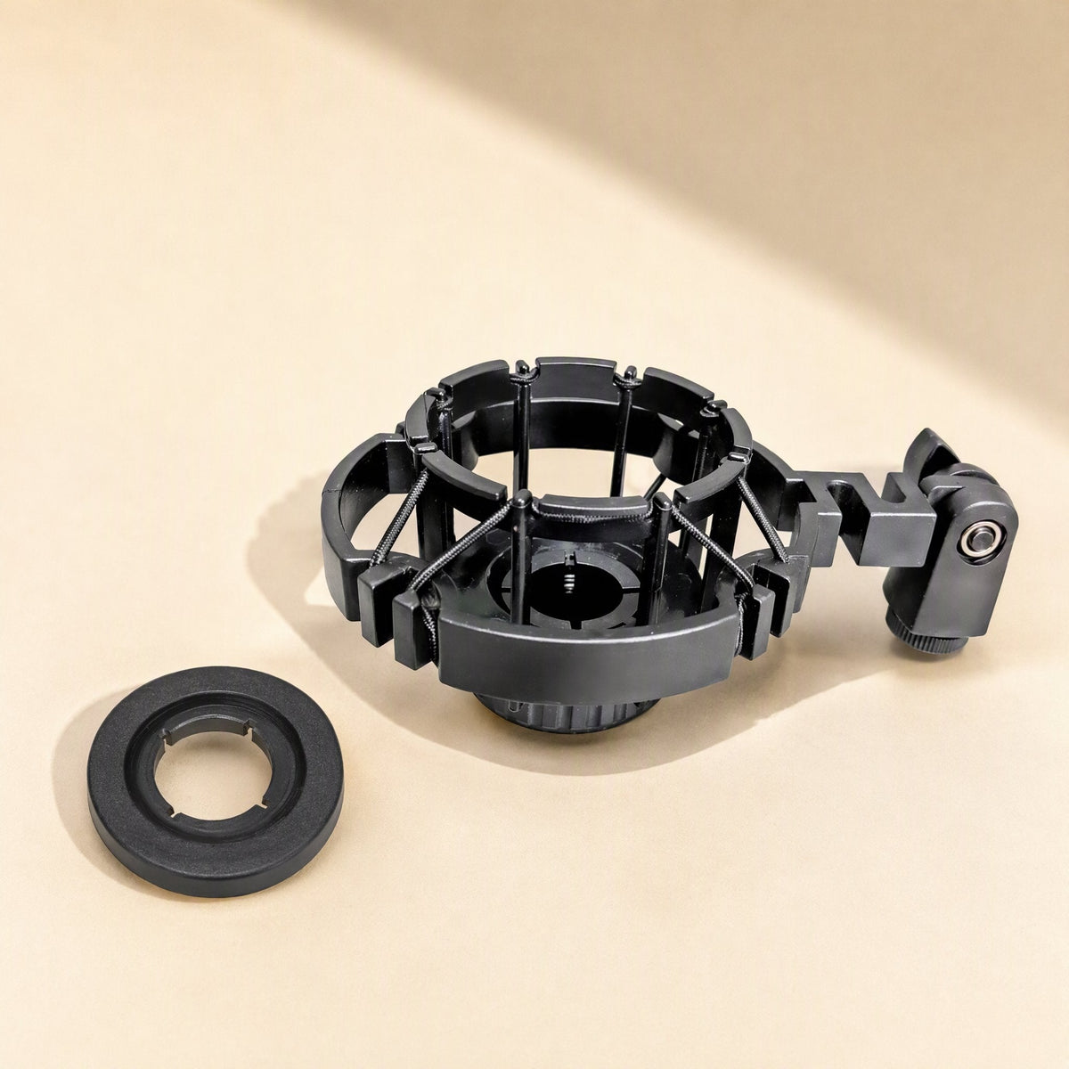 Micushion – Black cage-style shock mount with threaded stand adapter and separate round black ring beside it