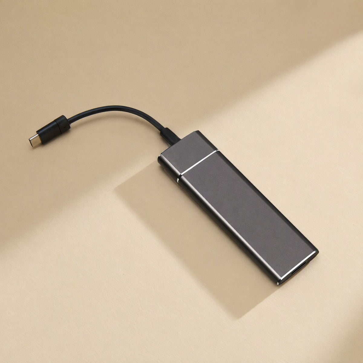 Driveforge – Dark gray slim drive on a beige surface with a black USB-C cable plugged into one end