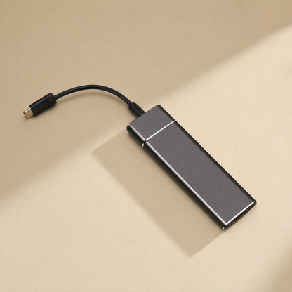 Driveforge – Dark gray slim drive on a beige surface with a black USB-C cable plugged into one end