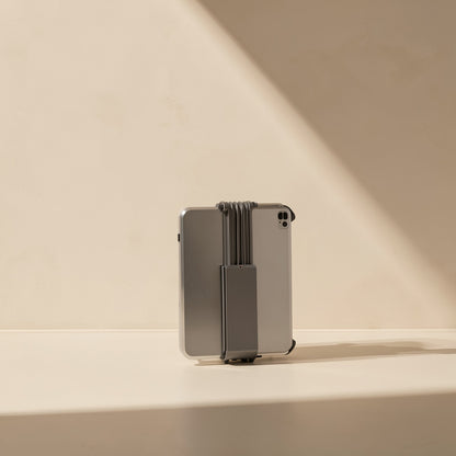 Rotaperch Rotary Phone and Tablet Stand folded flat, gray, holding a tablet from behind on a sunlit ledge
