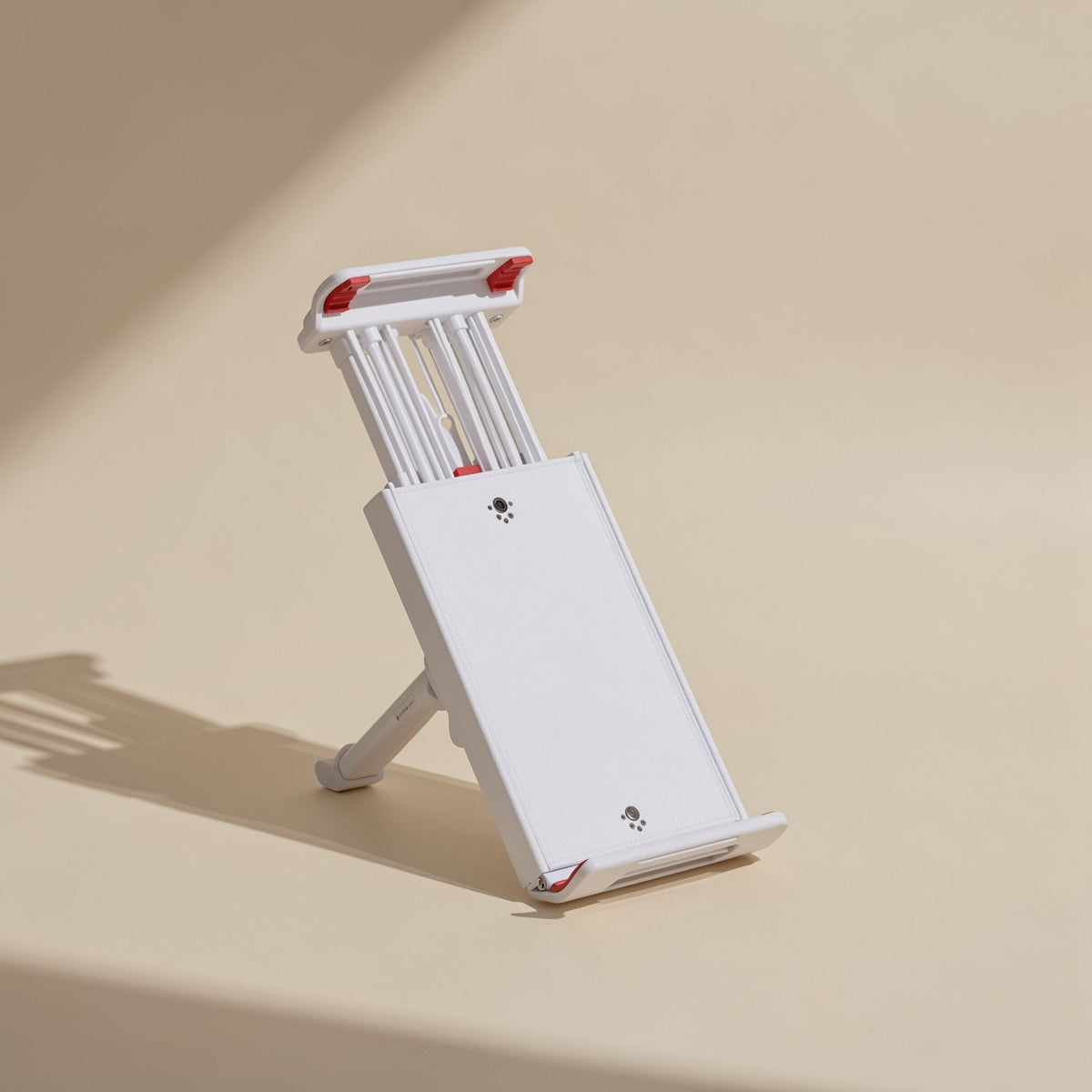 Rotaperch – White foldable stand with red-tipped clamp arms and a kickstand leg, standing on a tan surface