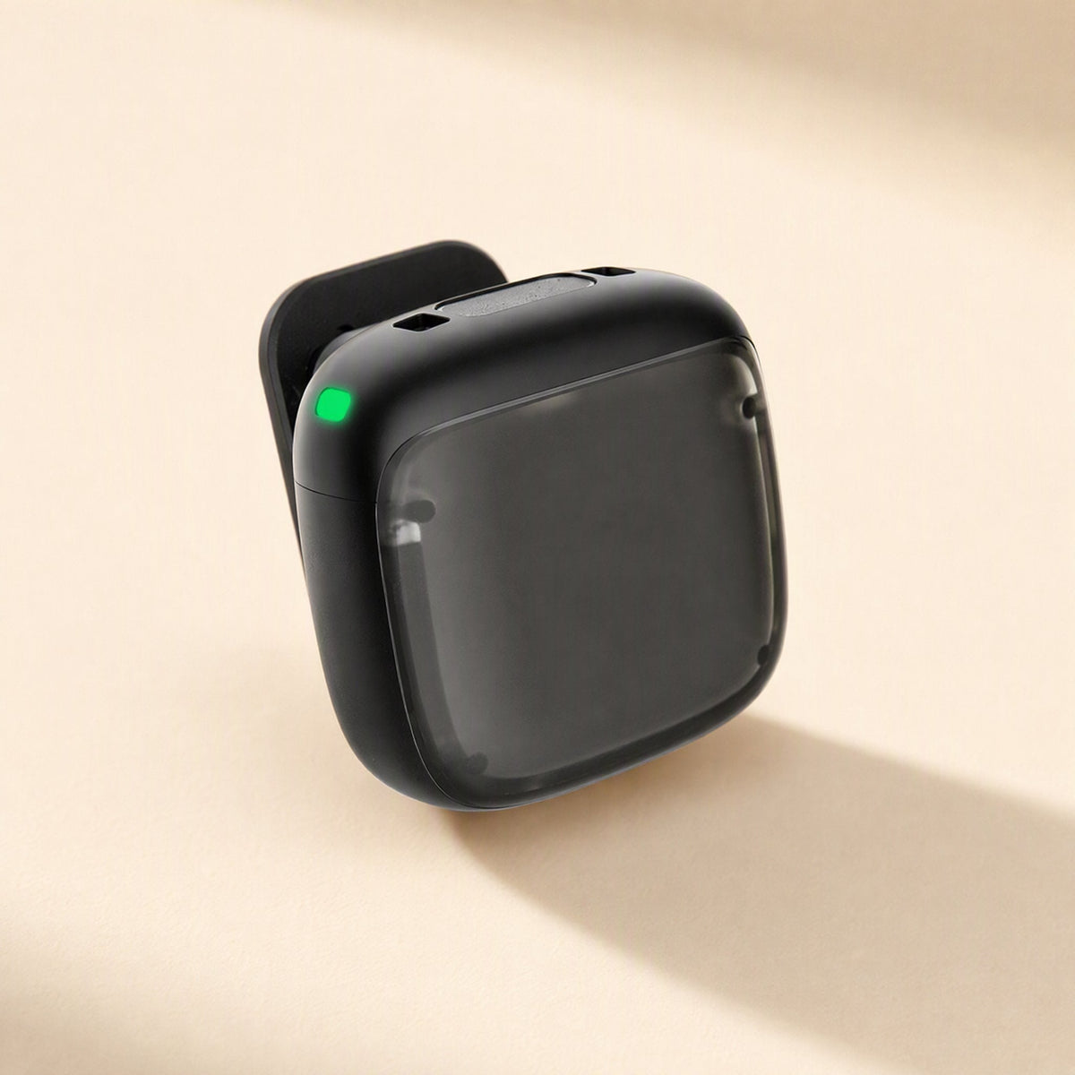 Noisehush – Single black clip-on transmitter with green indicator light on a beige background