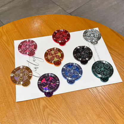 Discperch Desktop Phone Stand in nine colours with glittery flower centres laid out on a white sheet on a table