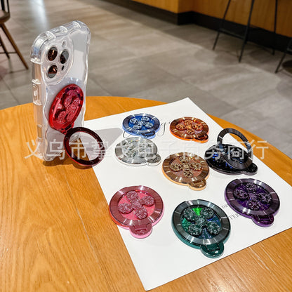 Discperch – Red stand mounted on a clear phone case, ring folded out, beside eight other colours on a wooden table