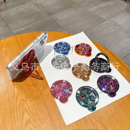 Discperch – Phone propped sideways on the red stand's folded ring, with eight other colours on the table beside it