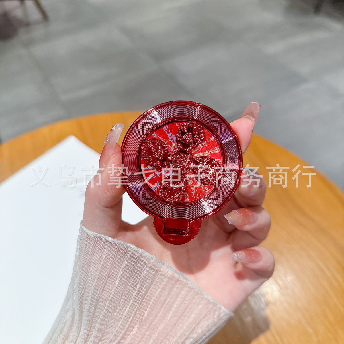 Discperch Desktop Phone Stand – hand holding a red CD-pattern stand with sparkly flower detail and a metallic rim