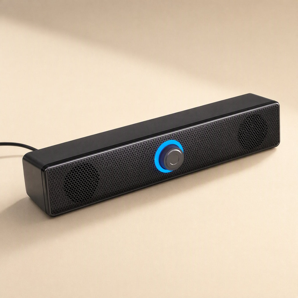 Wiretune – Black soundbar speaker with blue-lit center knob and cable trailing from the left end, on a beige surface