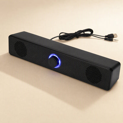 Wiretune – Black soundbar speaker with its USB and 3.5mm audio cable plugs laid out behind it, blue ring glowing