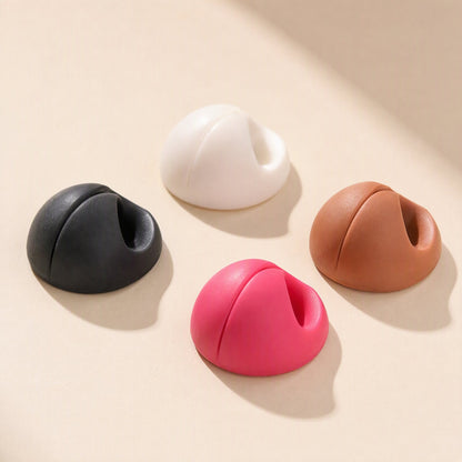 Cordslot Plastic Single-Hole Cable Organizer in black, white, brown and pink on a beige surface