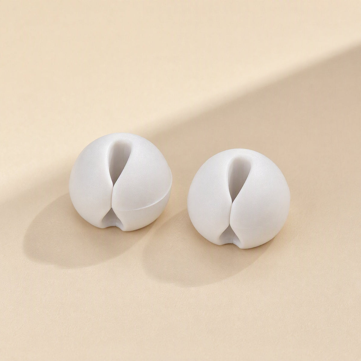 Cordslot – Two white cable organizers seen from the front, showing the central slot and narrow opening