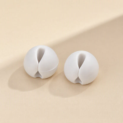 Cordslot – Two white cable organizers seen from the front, showing the central slot and narrow opening
