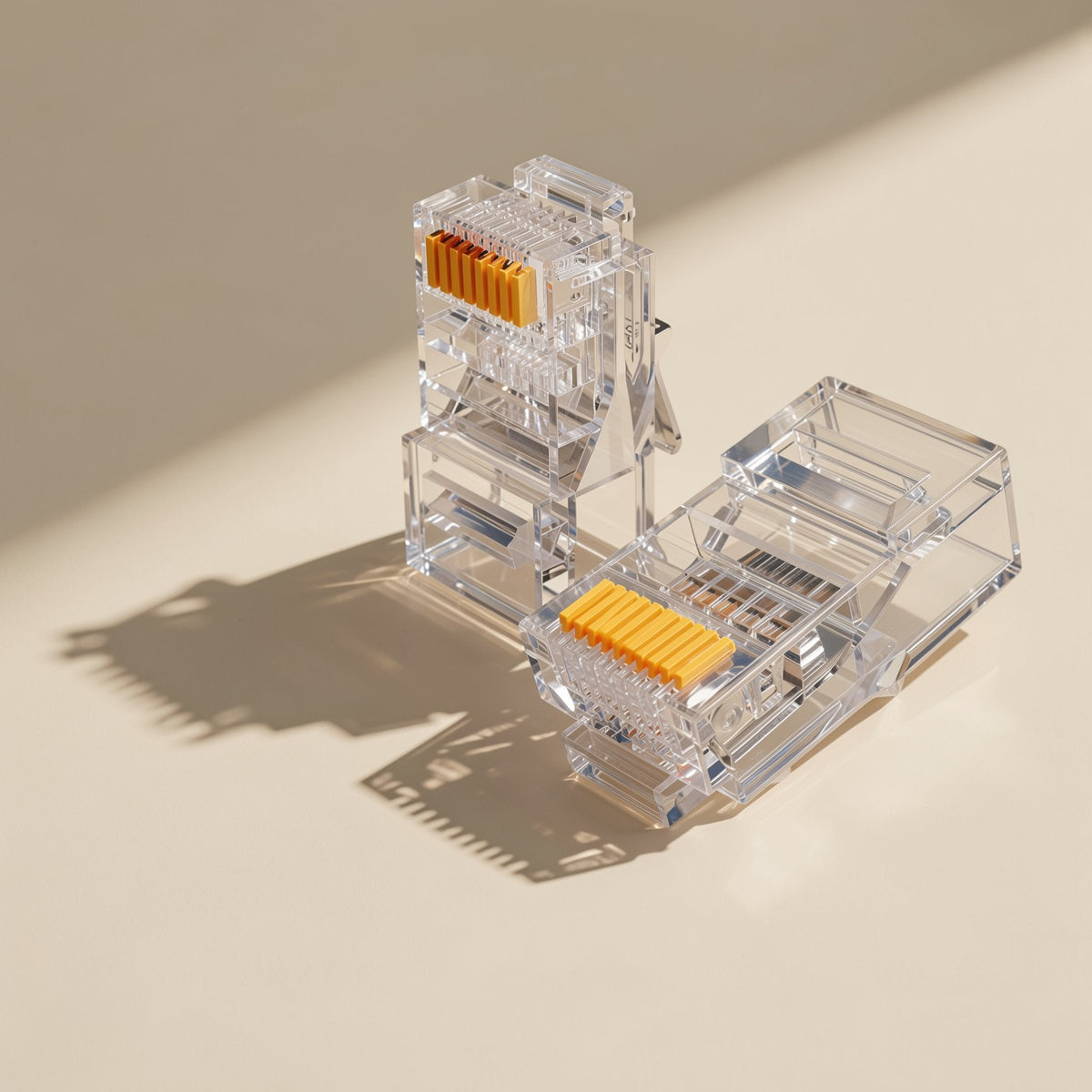Jackmate RJ45 network cable connectors, two clear plugs with gold contacts casting shadows on a cream surface