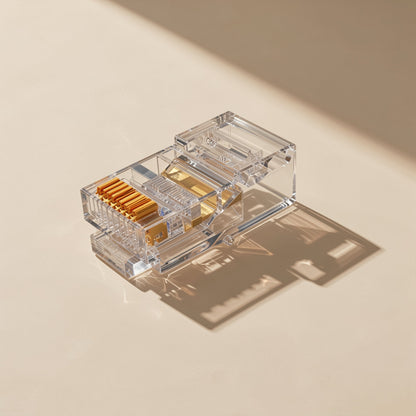 Jackmate – Single clear RJ45 connector seen from above, gold contact pins and latch on a beige surface in angled light