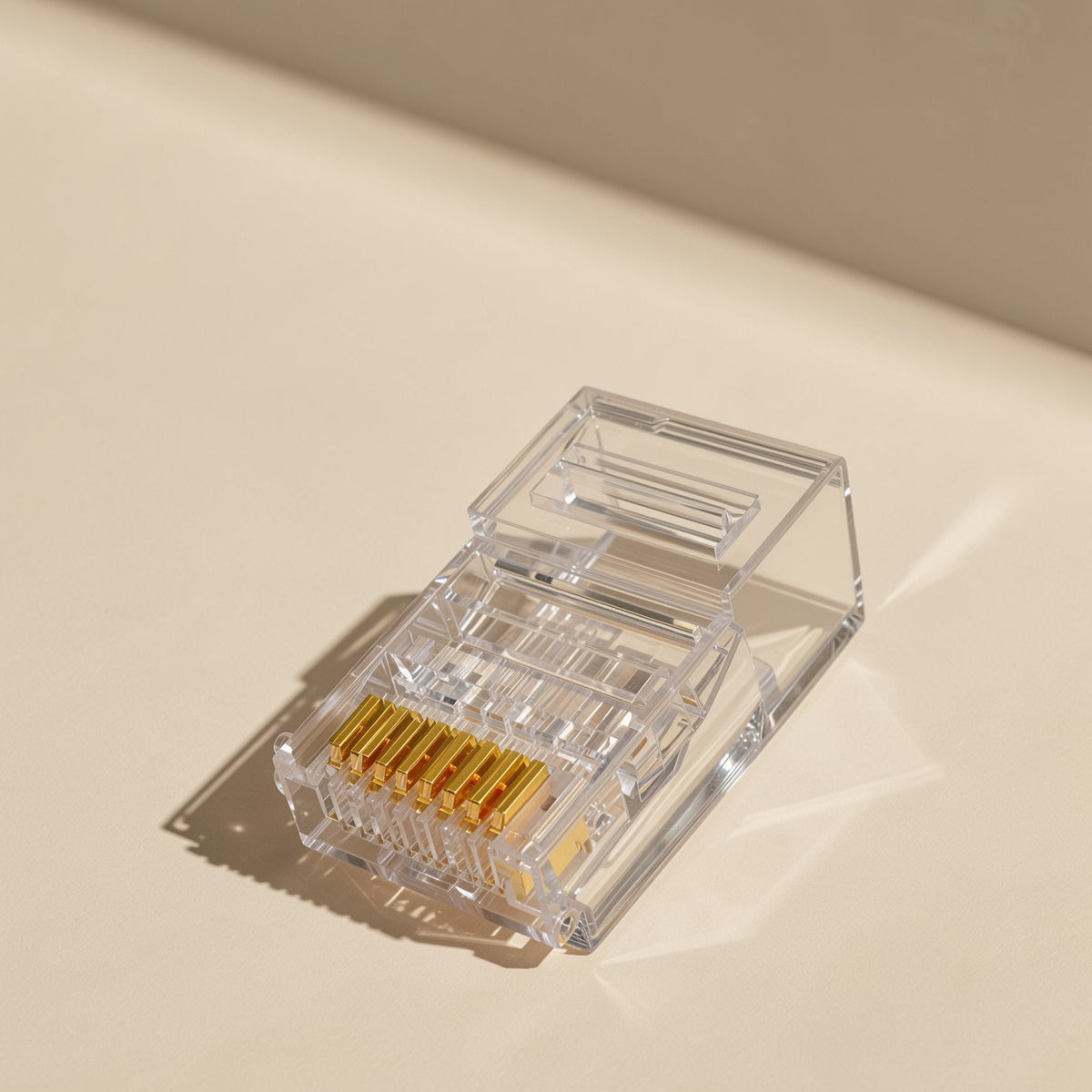 Jackmate – Clear 8P8C plug angled to show the row of eight gold pins and the raised latch tab on a cream background