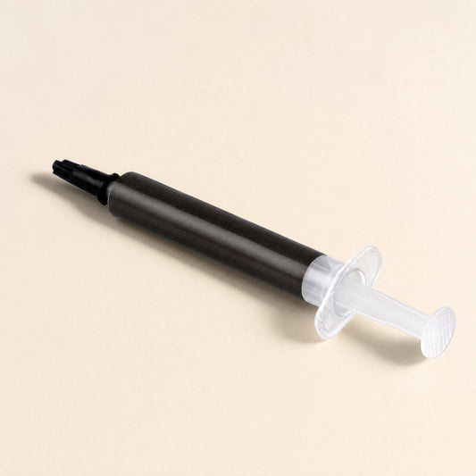 Thermaslip – Thermal paste syringe with black tip cap and clear plunger lying at an angle on a cream background