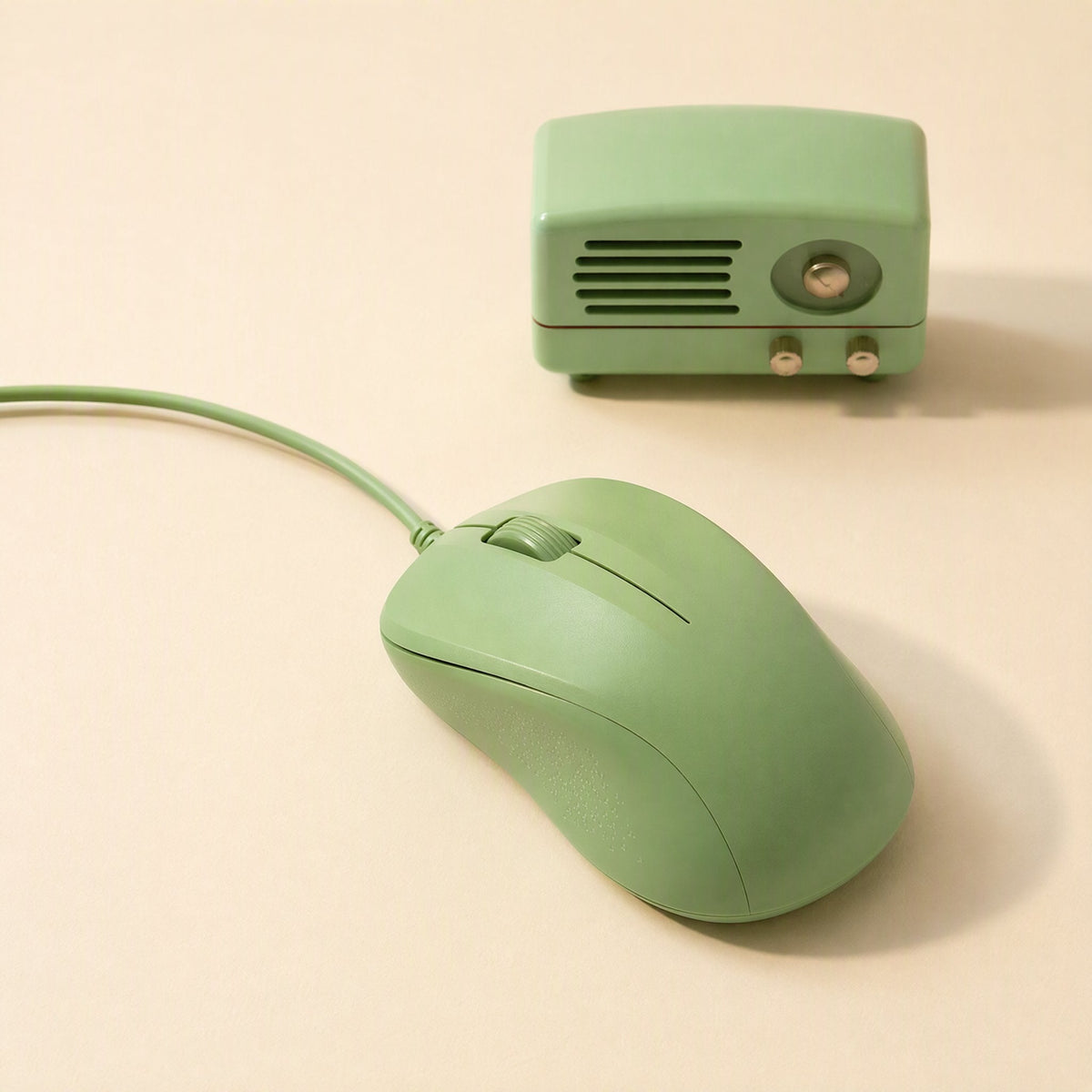 Deskcursor Wired Optical Mouse for Desktop – sage green wired mouse beside a small retro green radio on a cream surface