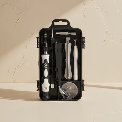 Screwkit – Black case holding the screwdriver handle, pry tools, tweezers and suction cup in the open lid, on a cream