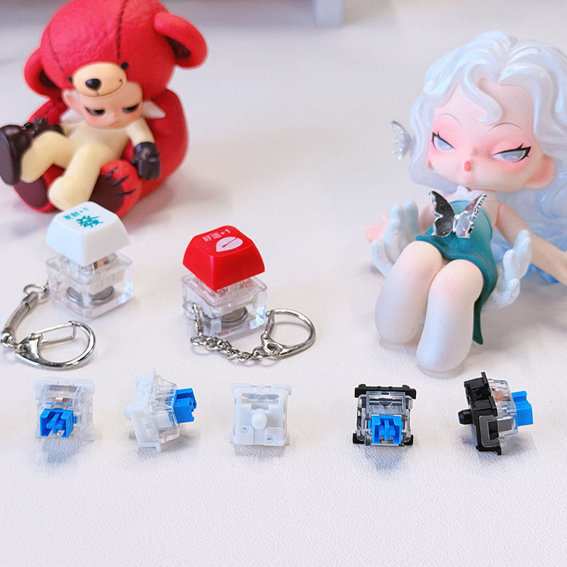 Crispop – Red and white keycap keychains above five blue switches in different angles, beside a teddy and a doll