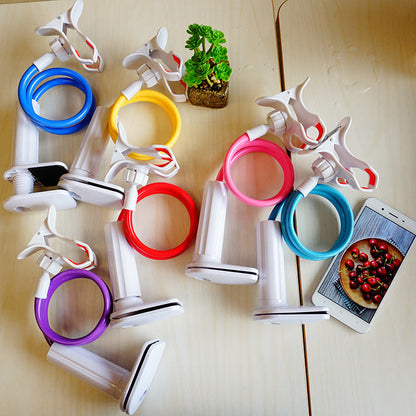 Coilrest Table Clamp Phone Stand in blue, yellow, red, pink, teal and purple on a wooden table beside a phone