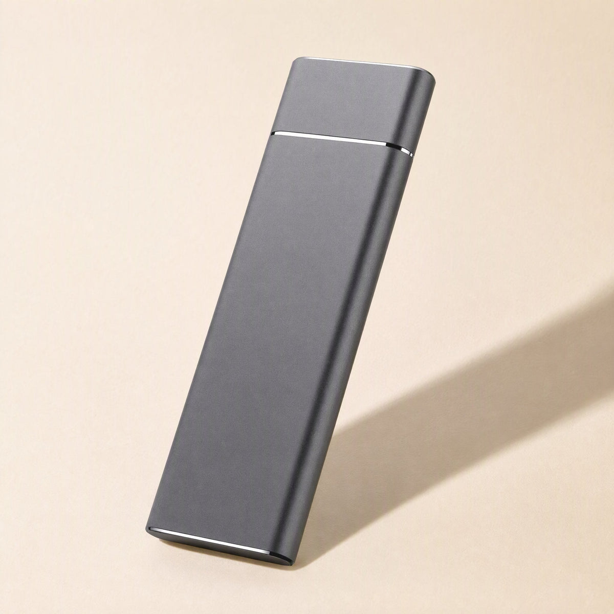 Pocketdrive – Slim gray aluminum drive standing upright on a beige background with a soft diagonal shadow
