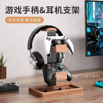 Timberhold Solid Wood Headphone Stand holding headphones and two game controllers on a desk beside a monitor
