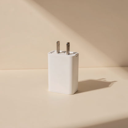 White wall charger plug with two metal prongs on a cream surface; no Colortie cable ties shown